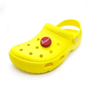 May include: Yellow Crocs clog with a red bottle top charm that says "Banquet" in white lettering.