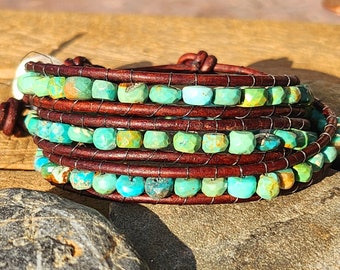 May include: A multi-wrap leather bracelet with turquoise beads. The bracelet is brown leather with a knotted closure. The turquoise beads are a mix of green and blue.