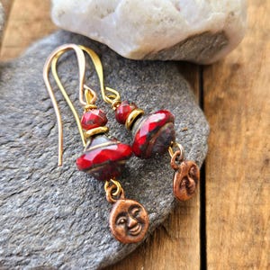 May include: A pair of dangle earrings with red and black glass beads and copper moon charms.