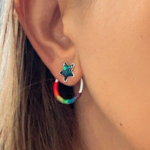 May include: A pair of rainbow hoop earrings with a small star stud earring in the other ear.