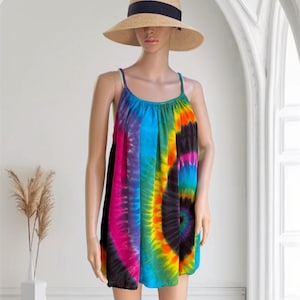 Könnte beinhalten: Eine Schaufensterpuppe trägt ein Batik-Kleid mit einem Regenbogenspiralen-Design. Das Kleid hat dünne Träger und eine lockere Passform. Die Schaufensterpuppe trägt auch einen Strohhut mit schwarzem Band.