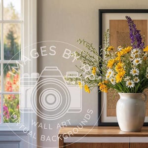 May include: A white ceramic vase with a bouquet of purple and yellow flowers. The vase is sitting on a wooden table in front of a framed print with text.