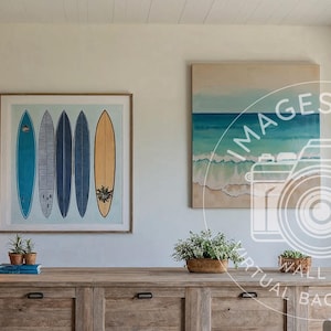 May include: A framed print of five surfboards in shades of blue and yellow hangs above a wooden cabinet. A second painting of a beach scene is to the right. A lamp with a decorative base sits on the cabinet.