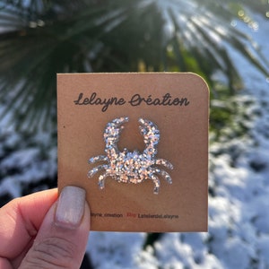 May include: A silver glitter crab on a brown card with the text "lelayne création" and "Etsy LatelierdeLelayne".