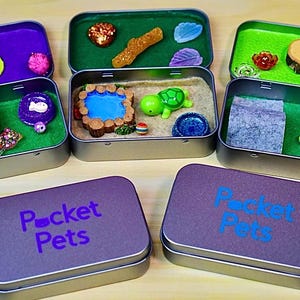 May include: Several small, open metal tins with miniature scenes inside. Each tin contains a different scene, including a cat, a turtle, and a bunny. The lids of the tins are purple and have the words "Pocket Pets" printed on them.