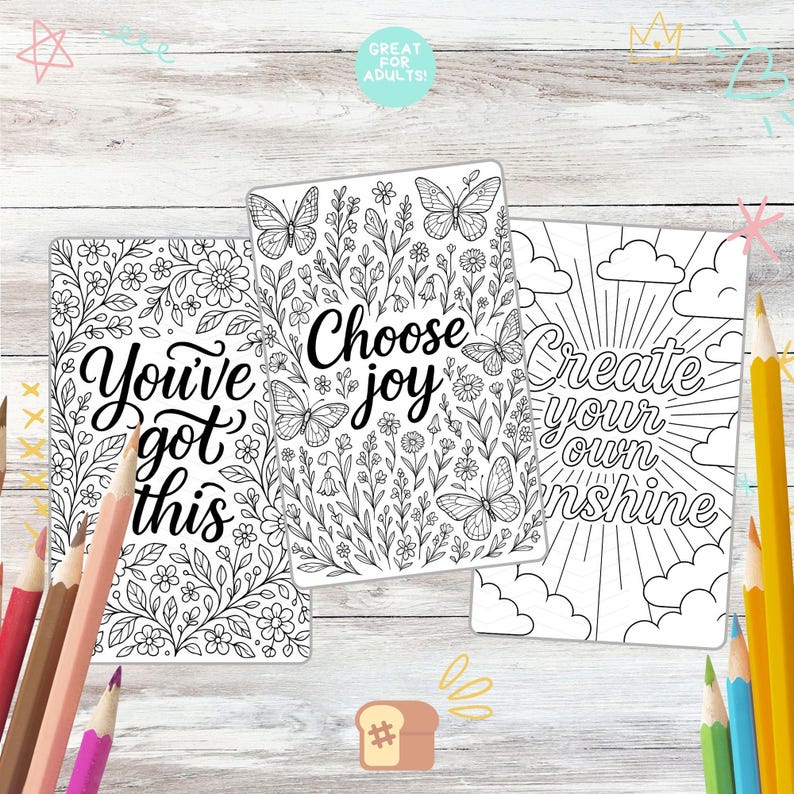 May include: Three adult coloring book pages with floral and butterfly designs. The pages have the phrases "You've got this", "Choose joy", and "Create your own sunshine". Colored pencils are scattered around the pages.