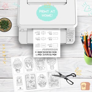 Puede incluir: Una impresora blanca imprimiendo una hoja con instrucciones para un mini libro para colorear. Debajo, una hoja de dibujos para colorear con tem&aacute;tica de terrarios y unas tijeras. El texto "PRINT AT HOME!" es visible.