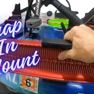 May include: A red and black fishing measuring board with the text "Snap In Mount" and "Fishing Online" is being assembled. The board has measurements in inches and is mounted on a blue kayak.