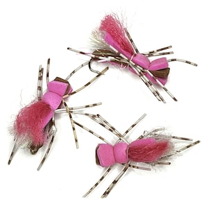 May include: Three pink and brown foam fly fishing lures with white and brown striped legs.