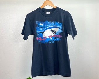 May include: Black t-shirt with a graphic of a great white shark jumping out of the water. The text "WILD THINGS" is printed in red and blue below the shark.