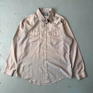 May include: A tan button-down shirt with long sleeves, two chest pockets, and a pointed collar. The shirt has white buttons and a small label on the collar. The fabric has a slight sheen.