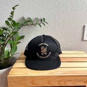 May include: Black mesh trucker hat with a gold embroidered logo that says "Fredonia Yellowjackets" and features a cartoon bee.