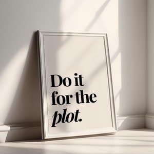 May include: A white framed print with the text "Do it for the plot." The print is leaning against a white wall in a room with a window.