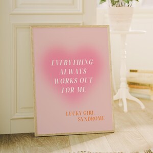 May include: A pink and white gradient poster with the text "Everything always works out for me. Lucky Girl Syndrome." in white and orange text.