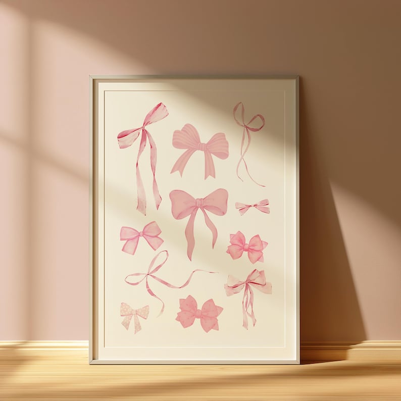 May include: A framed print featuring a collection of pink watercolour bows of various sizes and shapes. The bows are arranged in a random pattern on a white background.