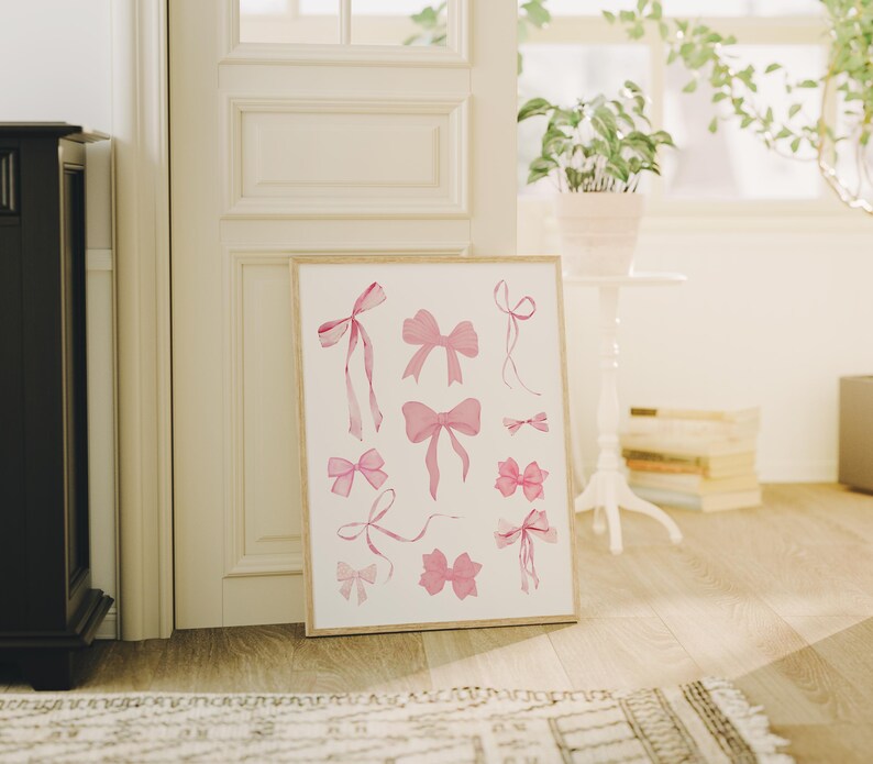May include: A printable art print featuring a collection of pink watercolour bows in various shapes and sizes. The bows are arranged in a symmetrical pattern on a white background.