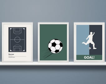 May include: Three framed prints with a soccer theme. The first print shows a black and white outline of a soccer field. The second print shows a white soccer ball with black panels flying through the air. The third print shows a white silhouette of a soccer player kicking a soccer ball with the word "GOAL!" printed below.