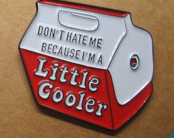 May include: Red and white enamel pin shaped like a cooler with the text "Don't hate me because I'm a little cooler".