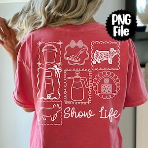 May include: A coral-colored t-shirt with white line drawings of farm-related items, including a bucket, brush, cow, spray bottle, barn, pig, and the words "Show Life". The shirt has a relaxed fit.