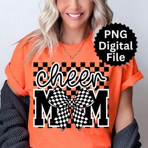 Puede incluir: Camiseta naranja con las palabras "cheer MOM" en fuente blanca y letras en bloque. Un lazo a cuadros blanco y negro est&aacute; centrado entre las palabras. Un gr&aacute;fico de estrella negra con el texto "PNG Digital File" est&aacute; en la esquina superior derecha.