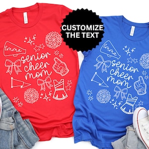 May include: Red and blue t-shirts with white graphic designs. The shirts feature the text "senior cheer mom" with cheerleading-related illustrations. The text "Customize the text" is also visible. White sneakers and denim are in the image.