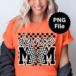 May include: Orange t-shirt with the words "dance MOM" in a black and white checkered design. The shirt has rolled-up sleeves and a black PNG file logo in the upper right corner.
