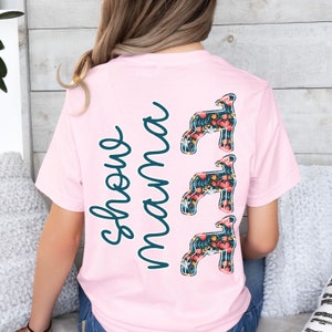 May include: Pink t-shirt with the text "Show mama" and three floral lamb silhouettes.