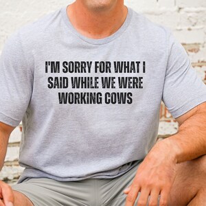 May include: A grey t-shirt with the text "I'm sorry for what I said while we were working cows" printed in black.