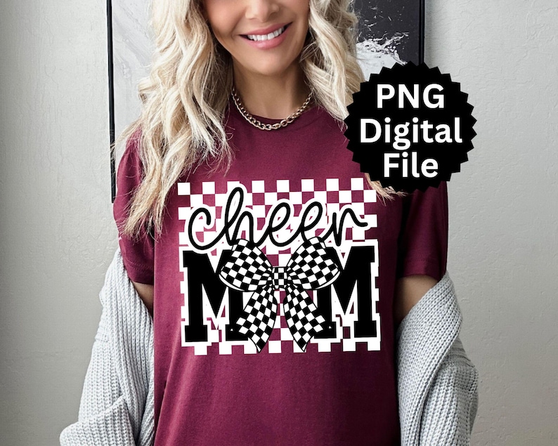Puede incluir: Camiseta burdeos con un dise&ntilde;o a cuadros blancos y negros. La camiseta presenta las palabras "cheer MOM" en una fuente audaz y estilizada, con un gr&aacute;fico de lazo a cuadros. Tambi&eacute;n hay un archivo digital PNG disponible.