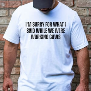 May include: White t-shirt with the text "I'm sorry for what I said while we were working cows" printed in black.