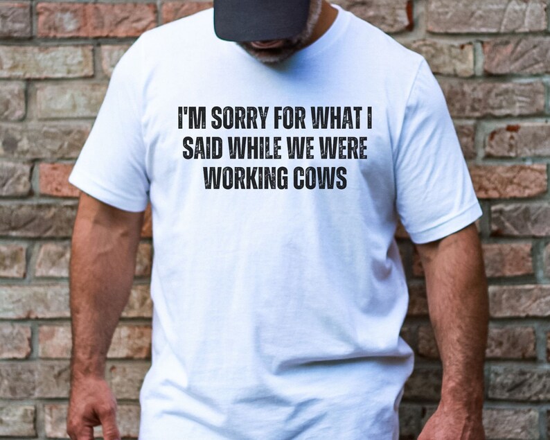 May include: White t-shirt with the text "I'm sorry for what I said while we were working cows" printed in black.