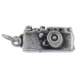 May include: A silver charm in the shape of a vintage camera. The camera has a textured surface and a round lens.