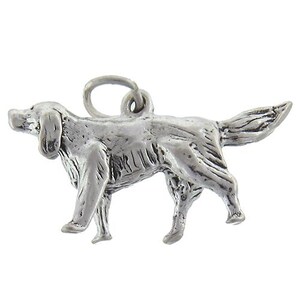 May include: Silver charm of a hunting dog, possibly a pointer or setter, in a running pose. The charm is detailed with a textured surface and a loop for attaching to a bracelet or necklace.