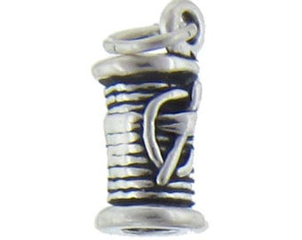 Puede incluir: Encanto de plata en forma de carrete de hilo con una aguja. El encanto está detallado con un carrete texturizado y una aguja envuelta alrededor del carrete.