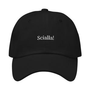 Pode incluir: Um boné de beisebol preto com a palavra Scialla! bordada em fio branco na parte frontal. O boné possui uma copa estruturada, uma aba curva e um botão no topo central. O design está centralizado no painel frontal do acessório.