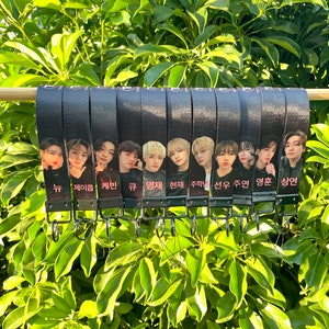 May include: A set of 10 black keychains with different member photos and names from the K-pop group,  "TXT" (Tomorrow X Together). The names on the keychains are: "Soobin", "Yeonjun", "Beomgyu", "Taehyun", "Hueningkai", "Jay", "Seungmin", "Chan", "Felix", and "Hyunjin".