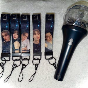 May include: A collection of five denim-textured wrist straps featuring images of people, with black hardware and lanyards. A dark blue light stick with a clear, spherical top is also present.