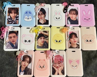 May include: A collection of rectangular plastic card holders in various pastel colors, each featuring a cartoon animal face or a portrait of a person. Several holders include attached beaded keychains with lettered beads spelling names.