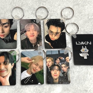 May include: A collection of rectangular keychains featuring images of people and a cartoon fox. The keychains have silver-colored metal rings. One keychain has the text "LYKN" and a cartoon fox.