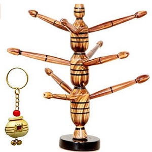 Könnte beinhalten: Ein hölzerner Teetassenhalter mit mehreren nach außen gerichteten Armen und ein kleiner dekorativer Schlüsselanhänger mit einem goldenen Ring und einem kleinen topfförmigen Anhänger. Der Halter ist braun mit schwarzen Streifen.
