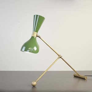 May include: A green and brass desk lamp with a unique, adjustable design. The lamp has a green, funnel-shaped shade and a brass base with a long, adjustable arm.