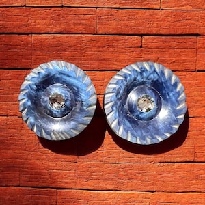 May include: A pair of blue and silver earrings with a clear crystal in the center of each earring.