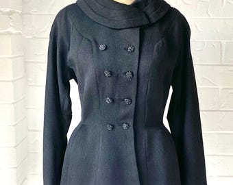 May include: A dark charcoal gray jacket featuring a wide, folded collar and a double-breasted front closure with four pairs of small, round, textured buttons. The jacket has long sleeves with folded cuffs and a tailored, fitted waist silhouette.