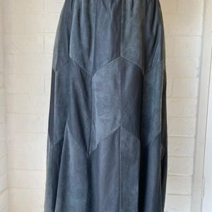 May include: A dark grey suede skirt with a geometric pattern. The skirt is knee-length and has a fitted waist.