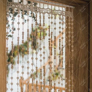 Könnte beinhalten: Eine Perlenvorhang mit abwechselnden Holzperlen und zylindrischen Teilen. Der Vorhang ist mit einer cremefarbenen, gehäkelten Volant versehen. Der Hintergrund zeigt einen Blick auf ein Fenster und einen Holzrahmen. Der Text "Qe Gifts Etsy.com" ist sichtbar.