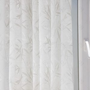 Puede incluir: Cortinas blancas y transparentes con un delicado patrón de hojas. Las cortinas están colgadas en una ventana y están ligeramente fruncidas.