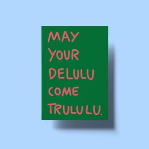Könnte beinhalten: Eine grüne rechteckige Karte mit dem Text "MAY YOUR DELULU COME TRULULU" in Rosa. Die Karte befindet sich vor einem hellblauen Hintergrund, mit einem Schatten darunter.