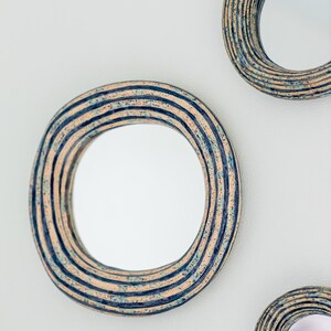 May include: Three circular wall mirrors featuring thick, textured frames with concentric ridges. The frames are finished in a speckled pattern of light beige, deep navy blue, and subtle teal tones, creating a layered, multi-colored appearance.