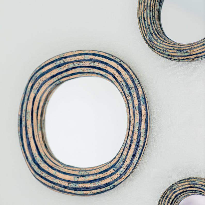 May include: Three circular wall mirrors featuring thick, textured frames with concentric ridges. The frames are finished in a speckled pattern of light beige, deep navy blue, and subtle teal tones, creating a layered, multi-colored appearance.