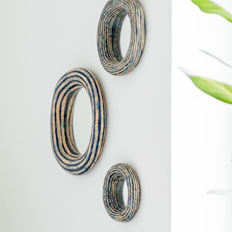 May include: Three circular wall mirrors of varying sizes, each featuring a thick, layered frame with a textured finish in shades of beige and dark blue. The frames exhibit a concentric, ribbed appearance with a speckled, mottled color pattern.